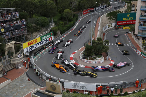 Multiple Formula 1 cars are navigating a tight hairpin at the Monaco Grand Prix