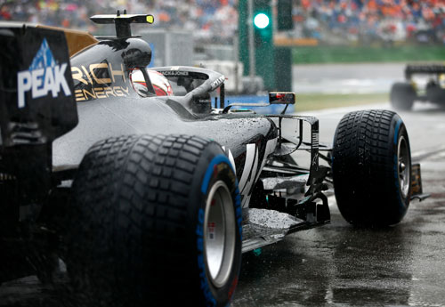 The black Haas car waits in the pit lane in the rain
