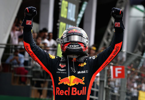 A Formula 1 driver, Max Verstappen, raises his hands in celebration